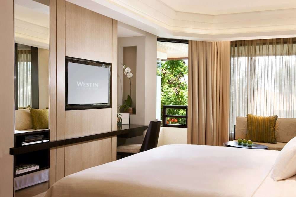 King bed with a work desk beside a garden-facing window