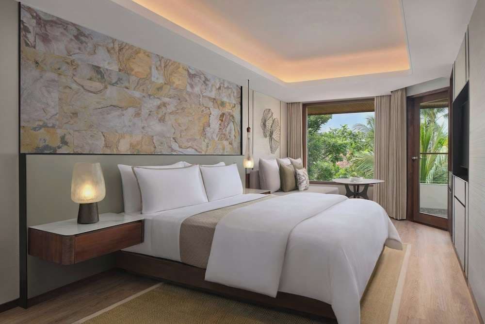 King bed beneath a stone feature wall, with balcony doors to the garden